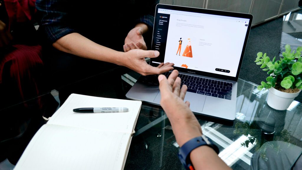 QA analysts discussing a project and looking at a computer